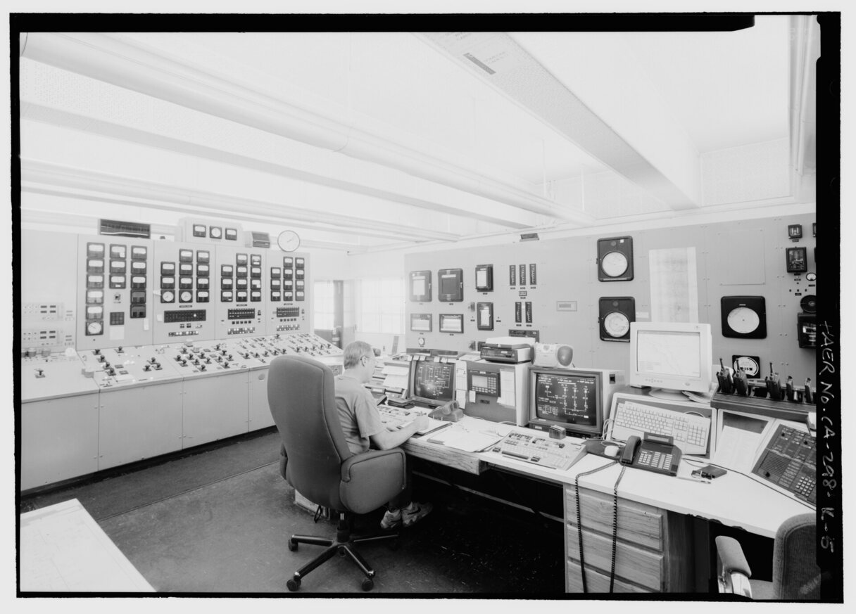 An empty power plant control room, one chair before a wall of panels and dials.