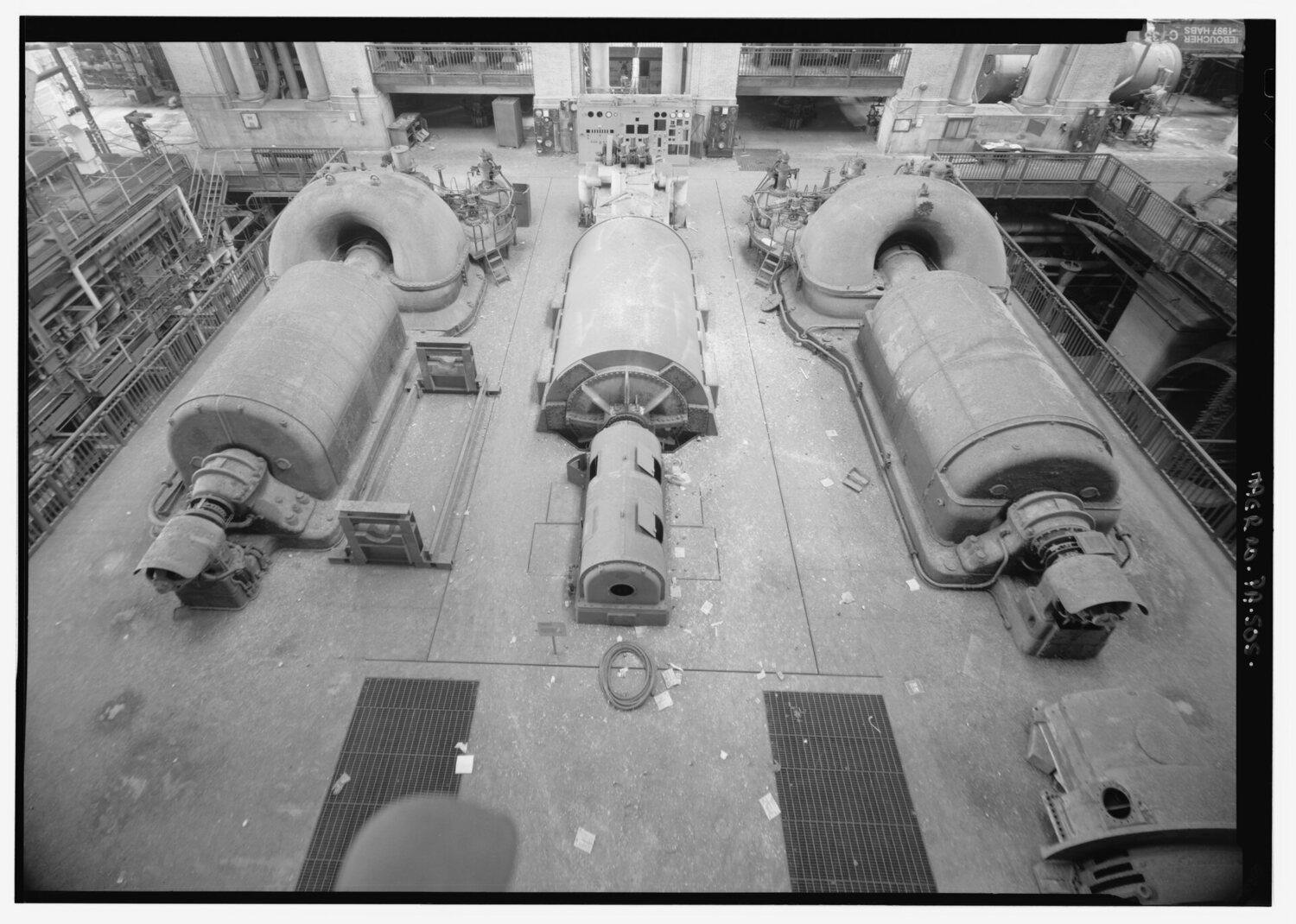 A turbine hall seen from the control room, generating units receding down the floor.